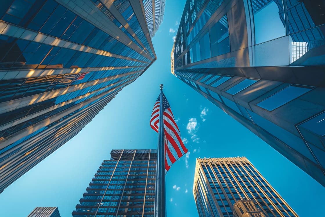 Upward view of glass office towers with a U.S. flag