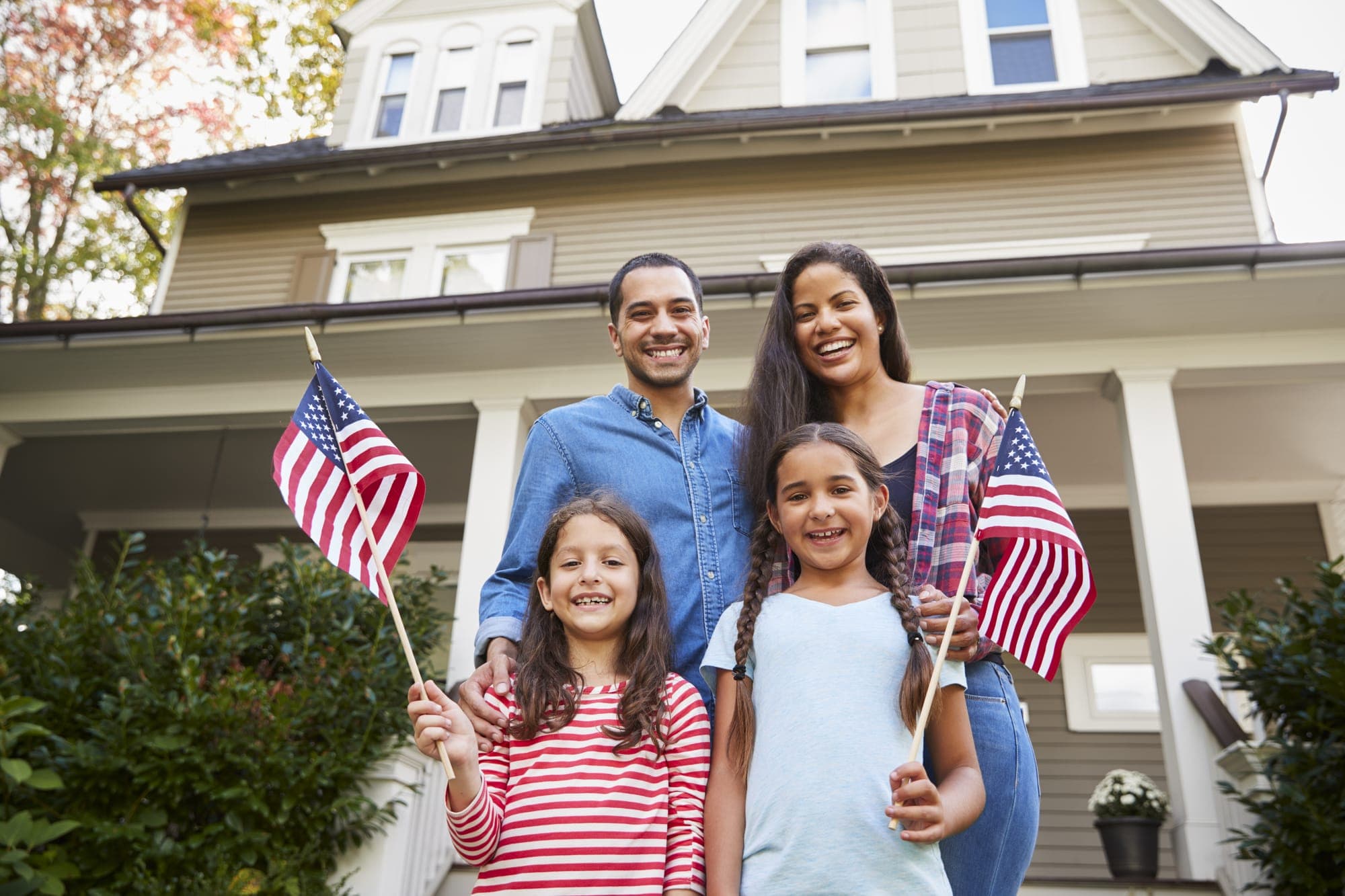 A family holding US flags outside their American home